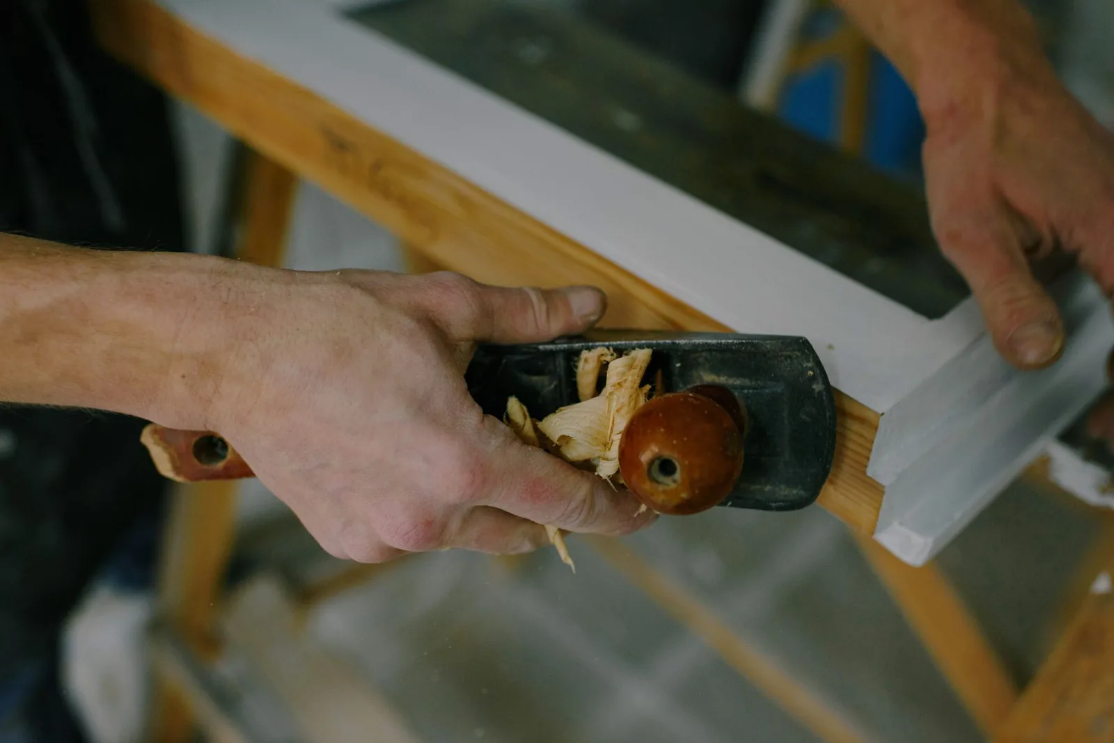 Hands running a block plane along a length of timber