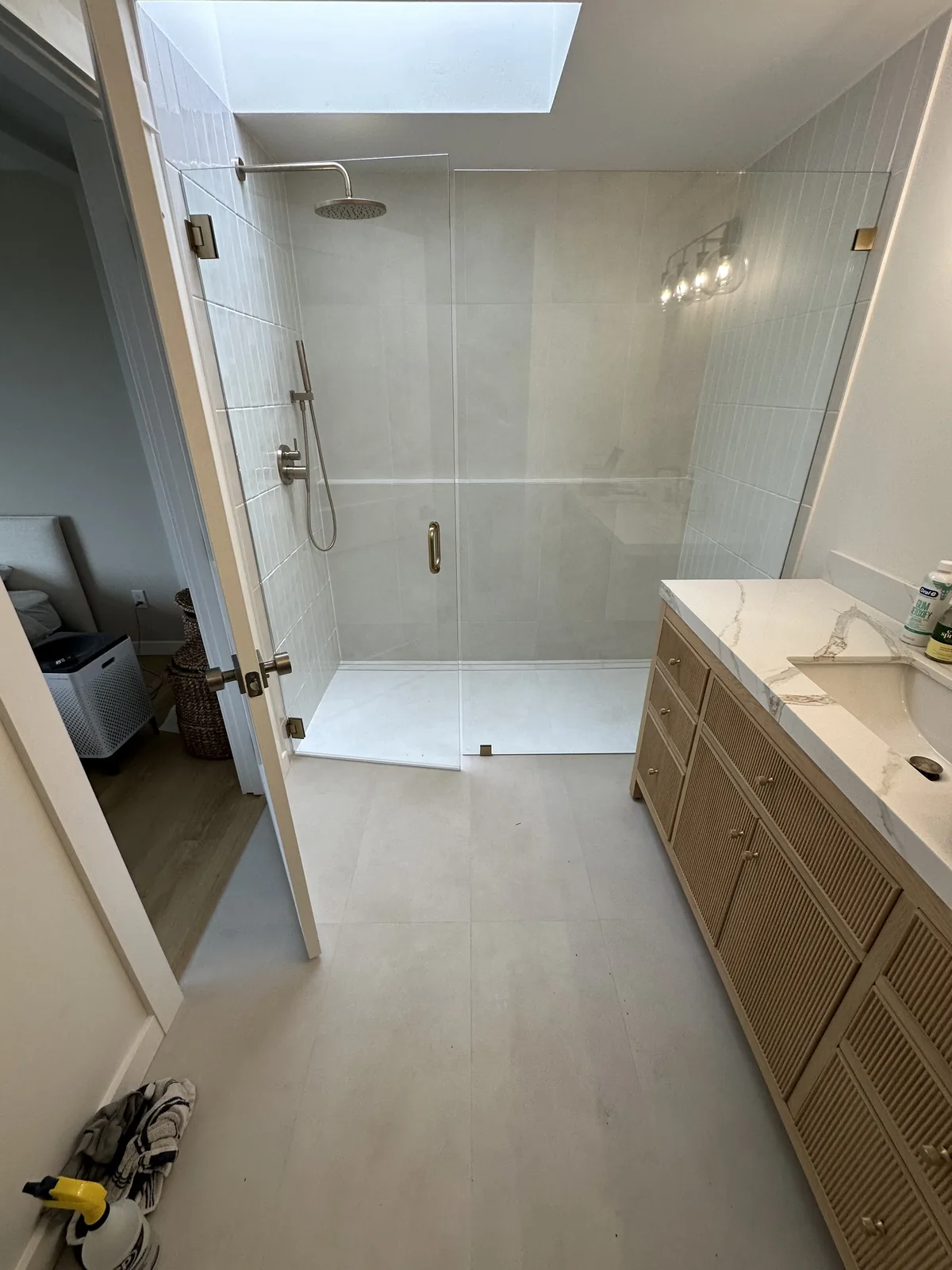 Modern bathroom with a frameless glass shower, skylight and fluted wood vanity