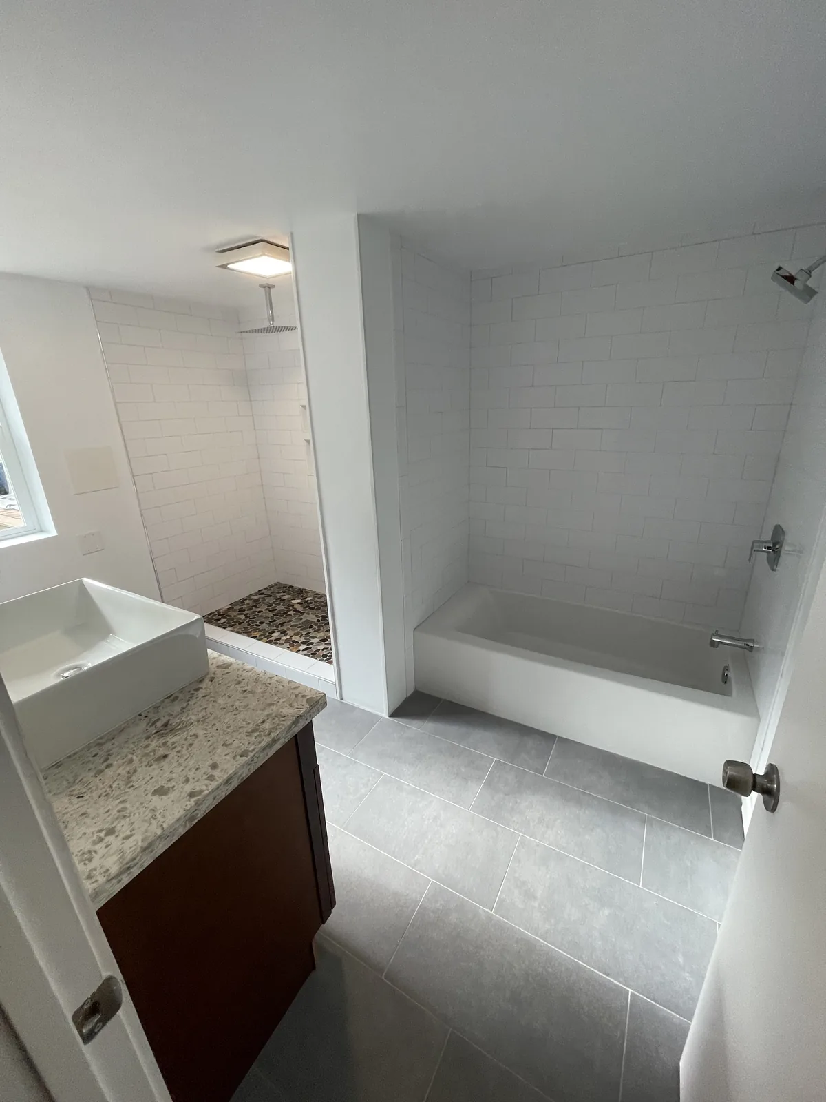 Bathroom with white subway-tiled shower and tub and a vessel-sink vanity