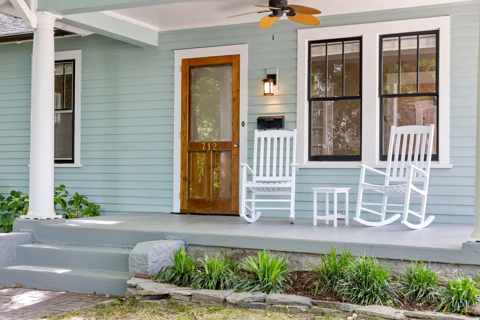 Front porch with white rocking chairs beside a wooden front door