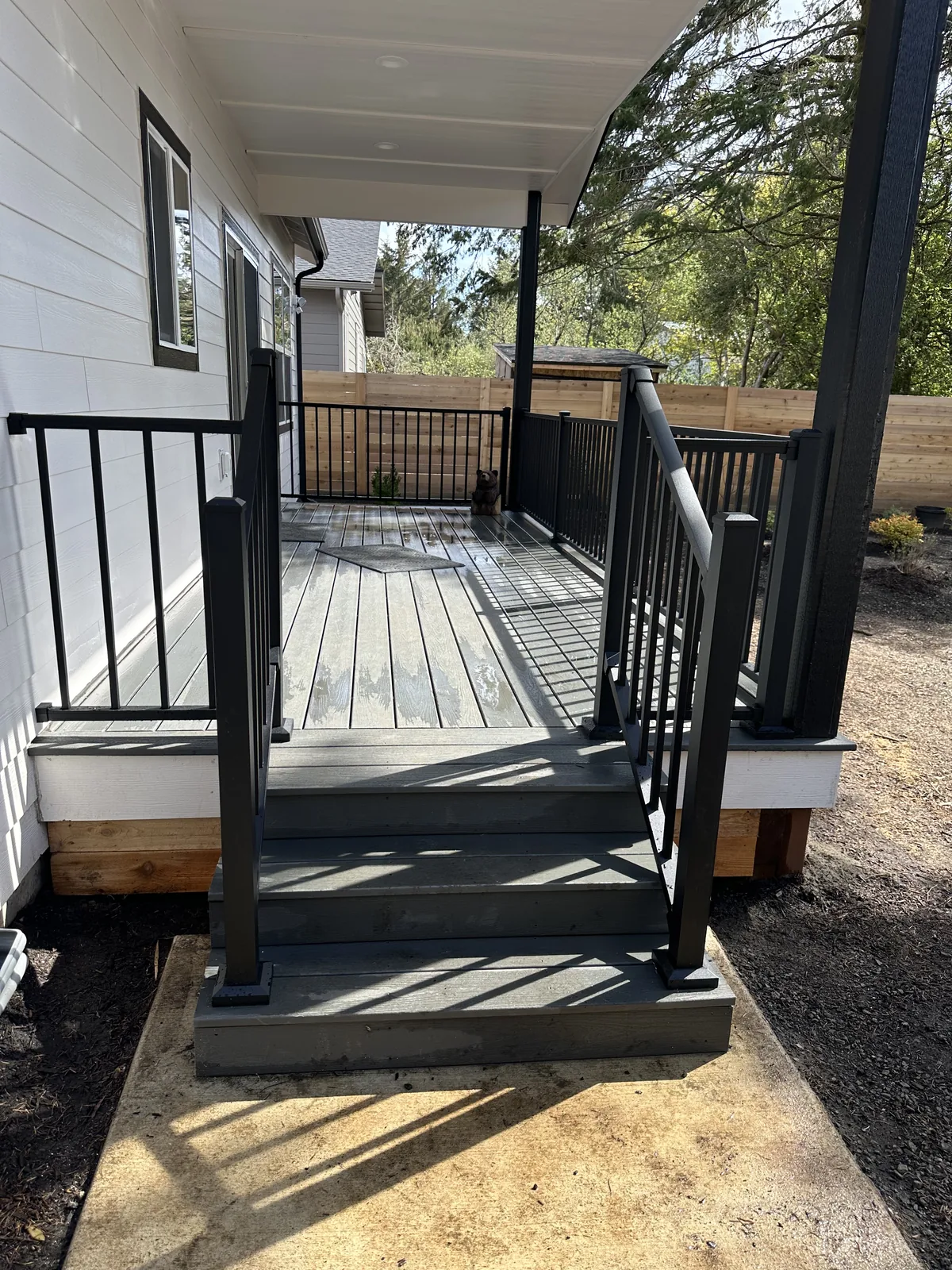 New grey composite deck with black metal railings under a covered porch