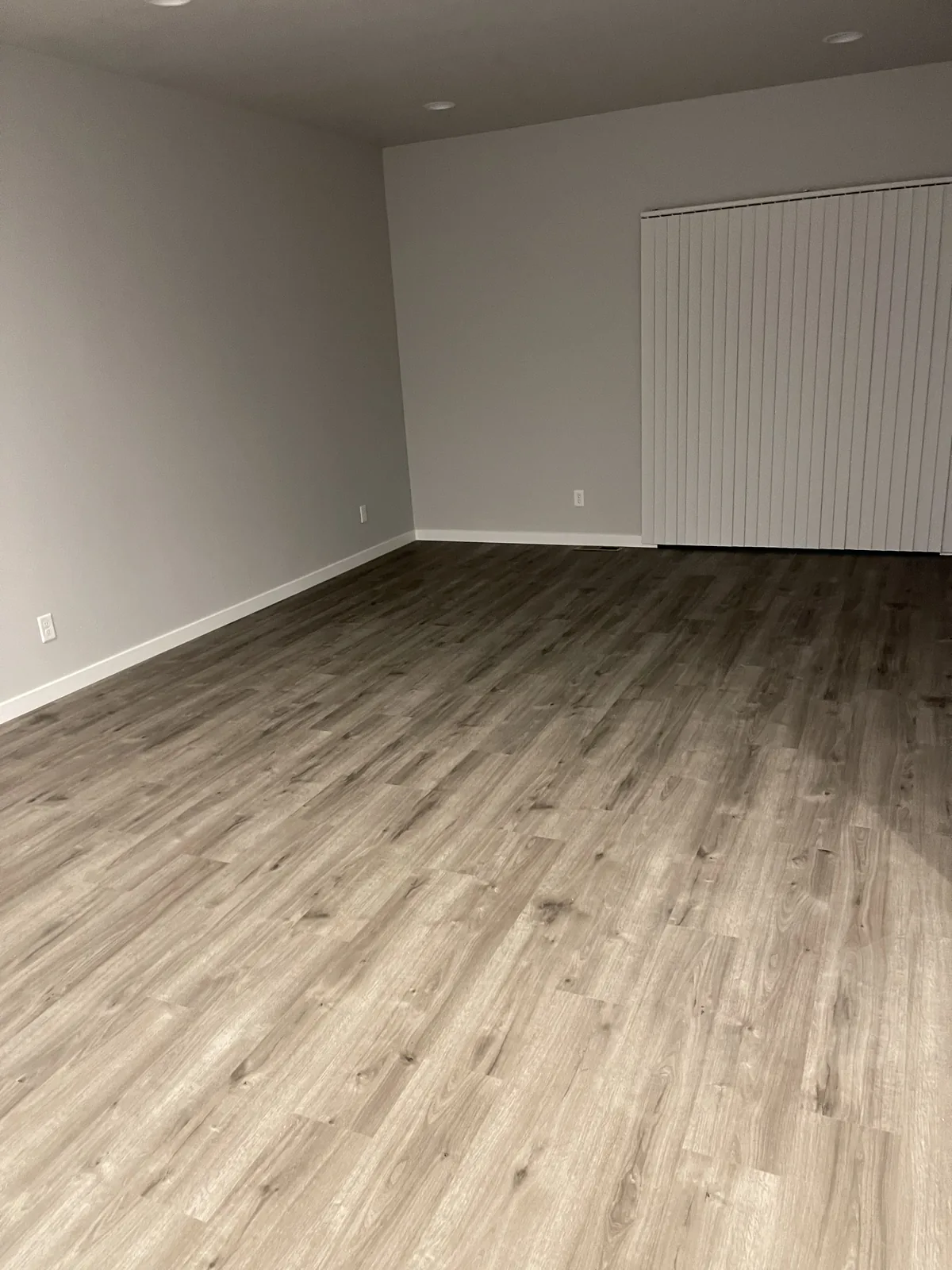 Empty room with newly laid grey wood-look flooring and fresh paint