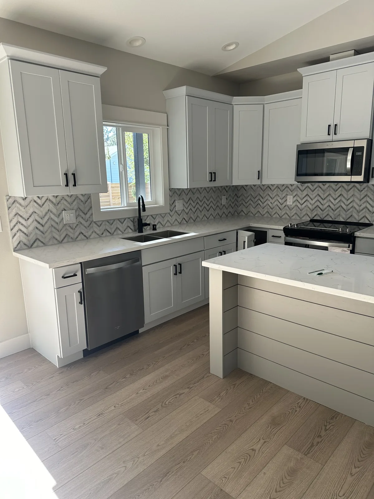 Kitchen with grey shaker cabinets, a marble chevron backsplash and a breakfast peninsula