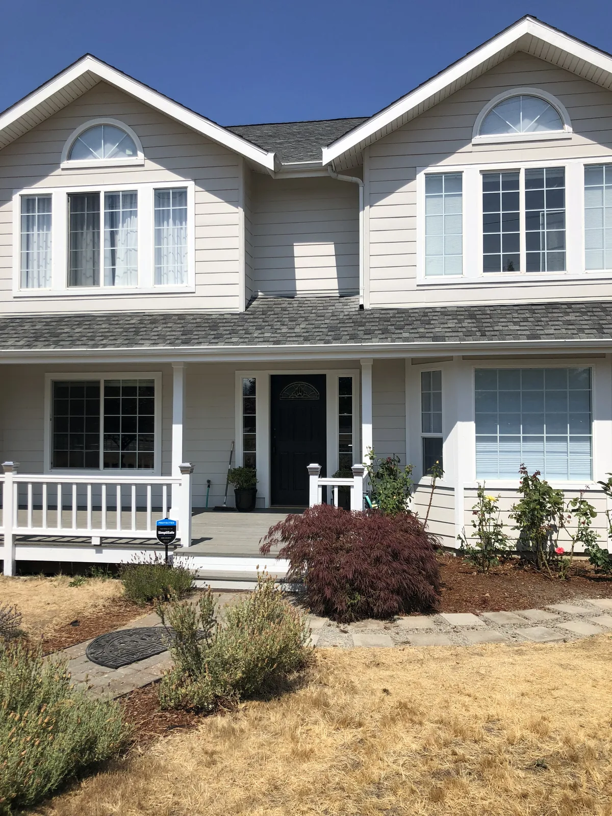 Covered porch with newly painted grey siding, white columns and a beadboard ceiling