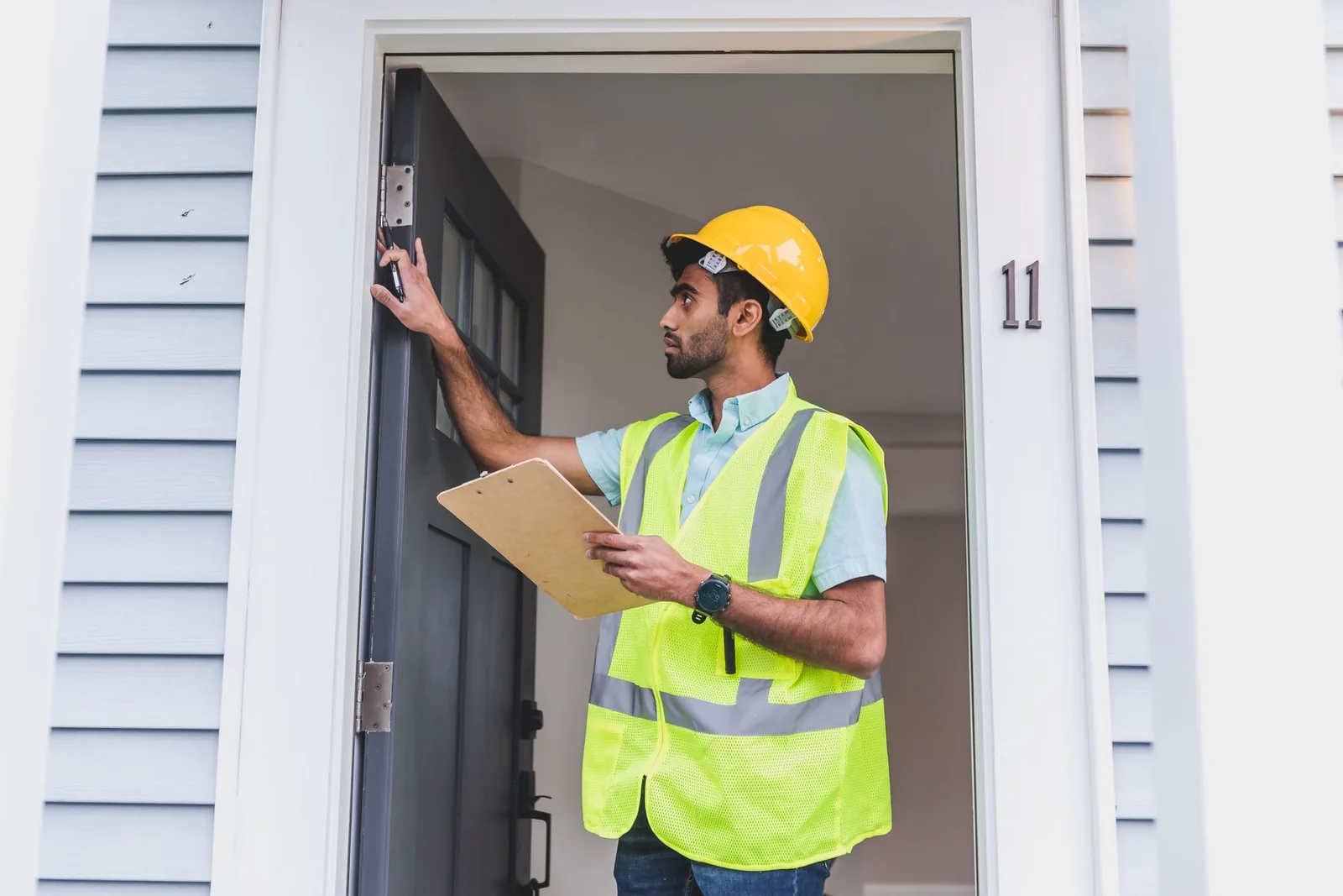 Contractor checking a door frame with a clipboard during a walk-through