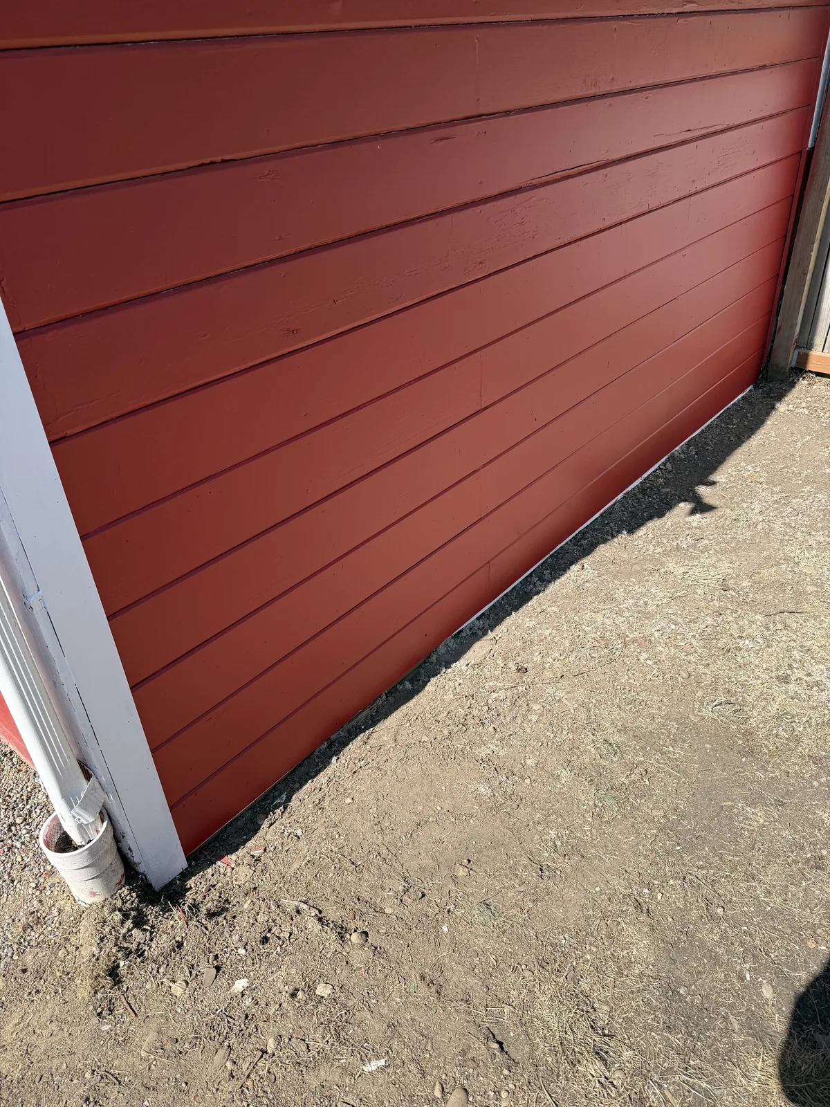 Repaired red lap siding painted to match after the board replacement